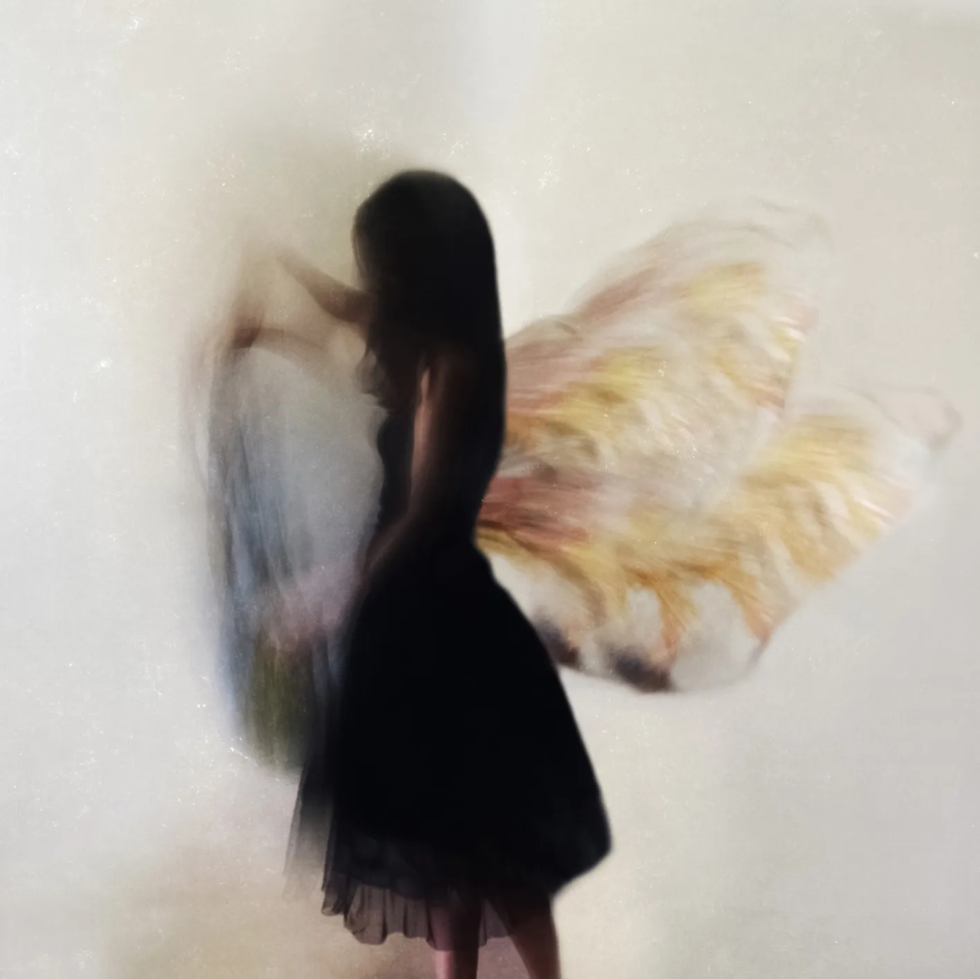 Woman in a black dress wearing colorful angel wings