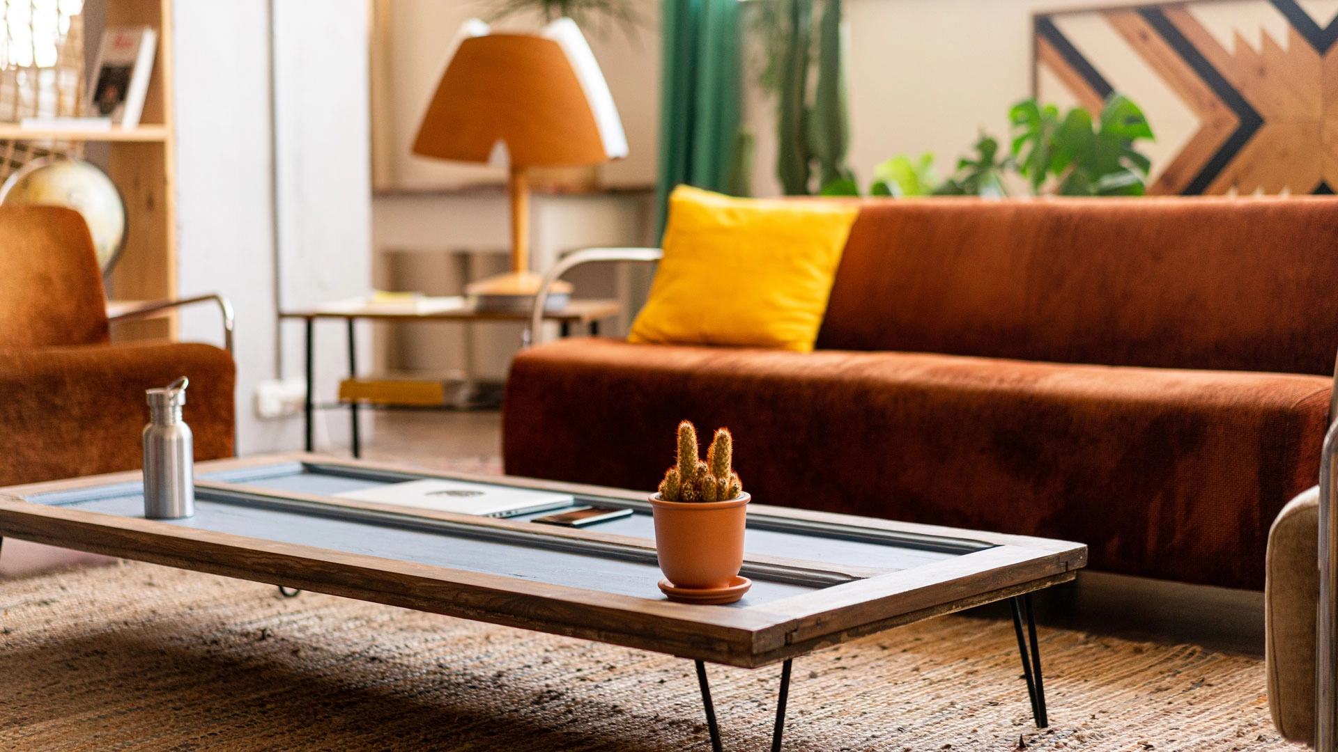 Photograph of a sunny living room with furniture in brown, yellow, and orange. 