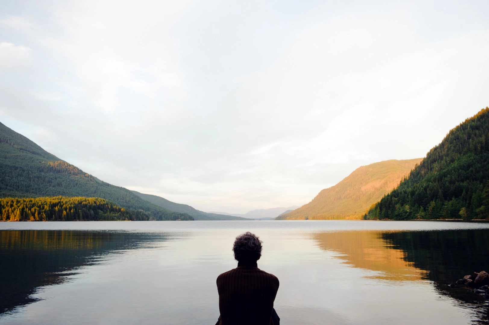 Person sits alone by a lake healing from feelings of loneliness after a divorce.