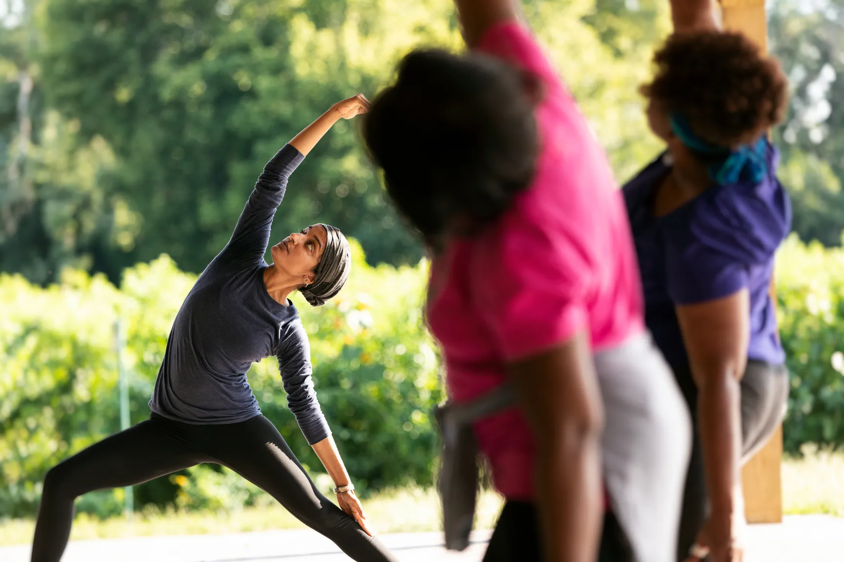 Yoga teacher leads students in Warrior pose in an outdoor class 