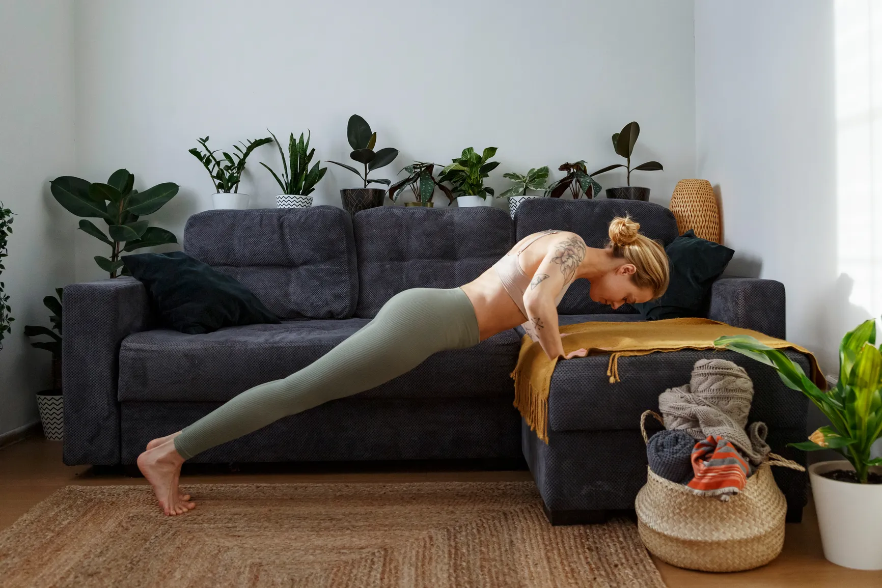 Woman does push ups on the couch in her home as part of a beginner primal movement workout flow.