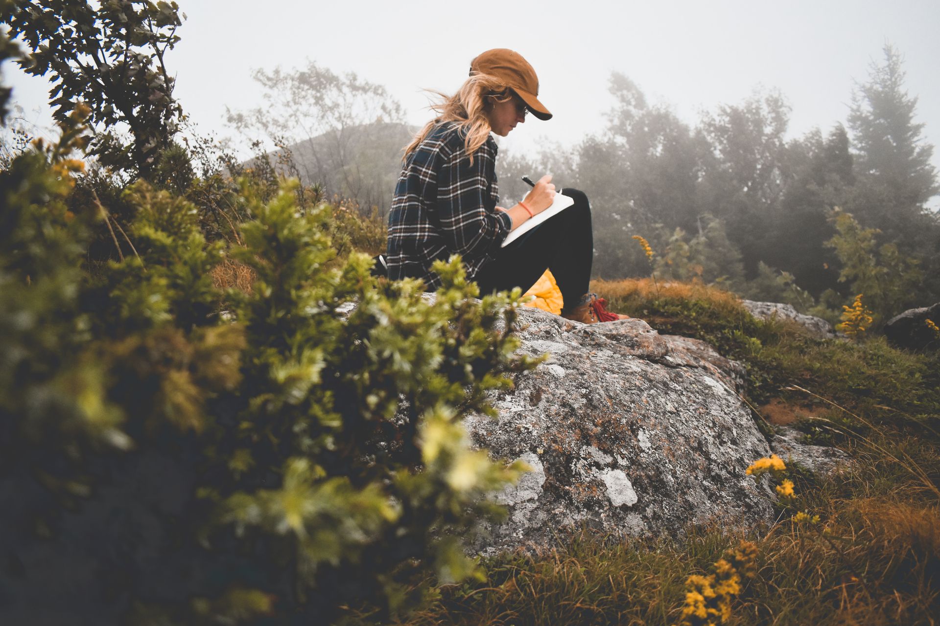 Woman journaling alone in the outdoors to prepare for a difficult father's day gathering 