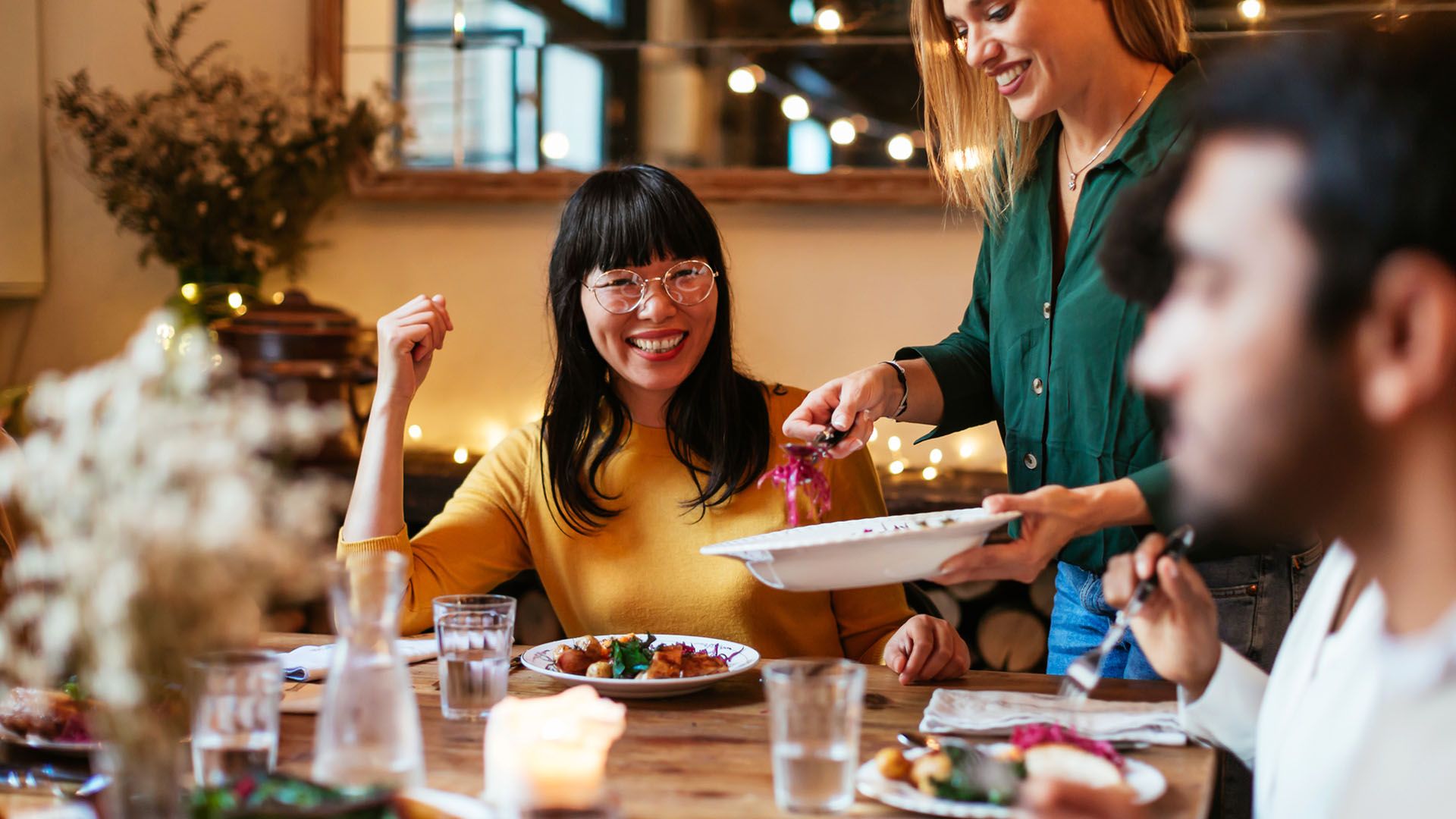 Group of friends smiling and sitting around a table at a festive dinner party.