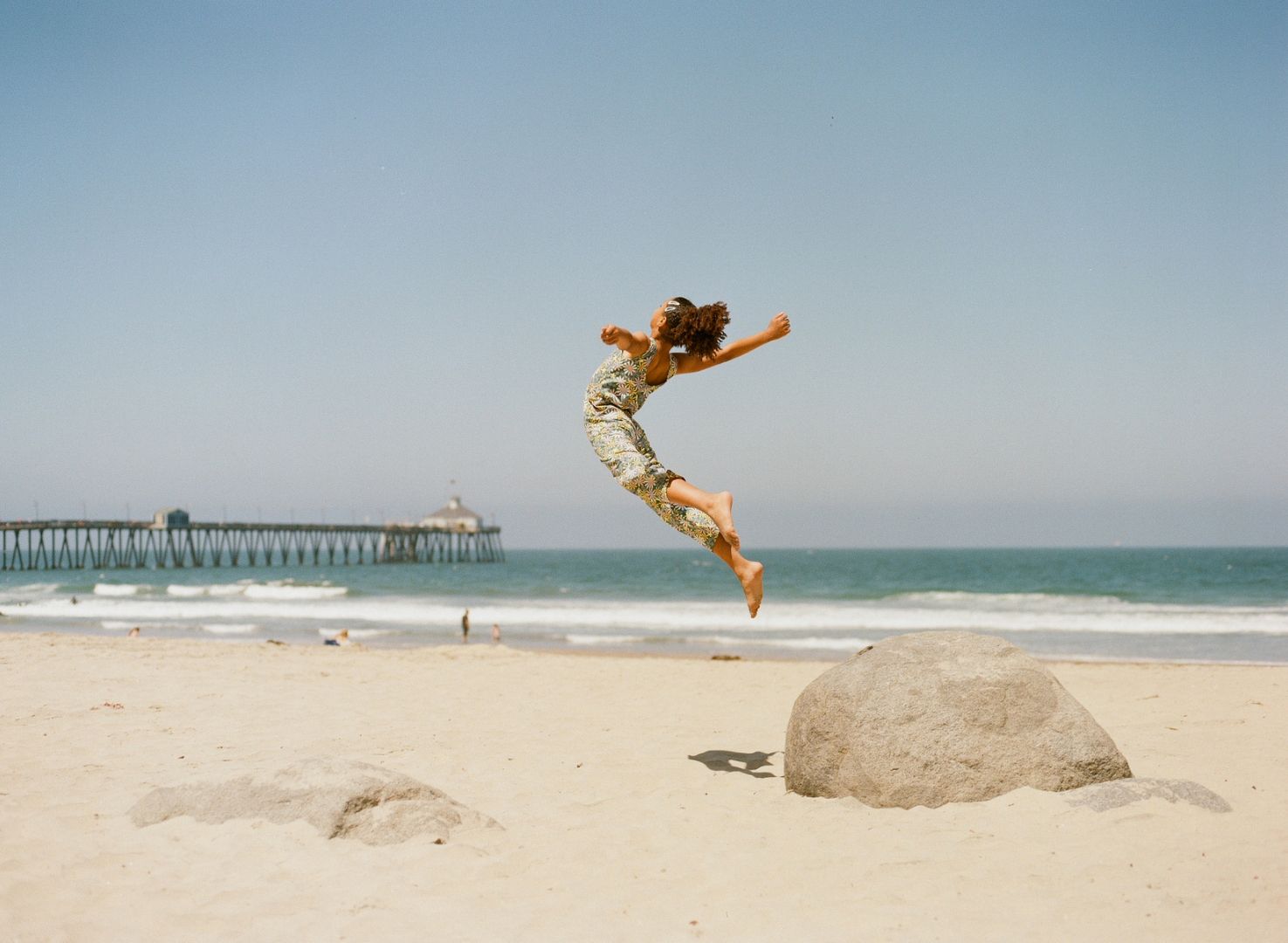 A woman jumps for joy on a sunny, beautiful beach, celebrating the start of a new year.