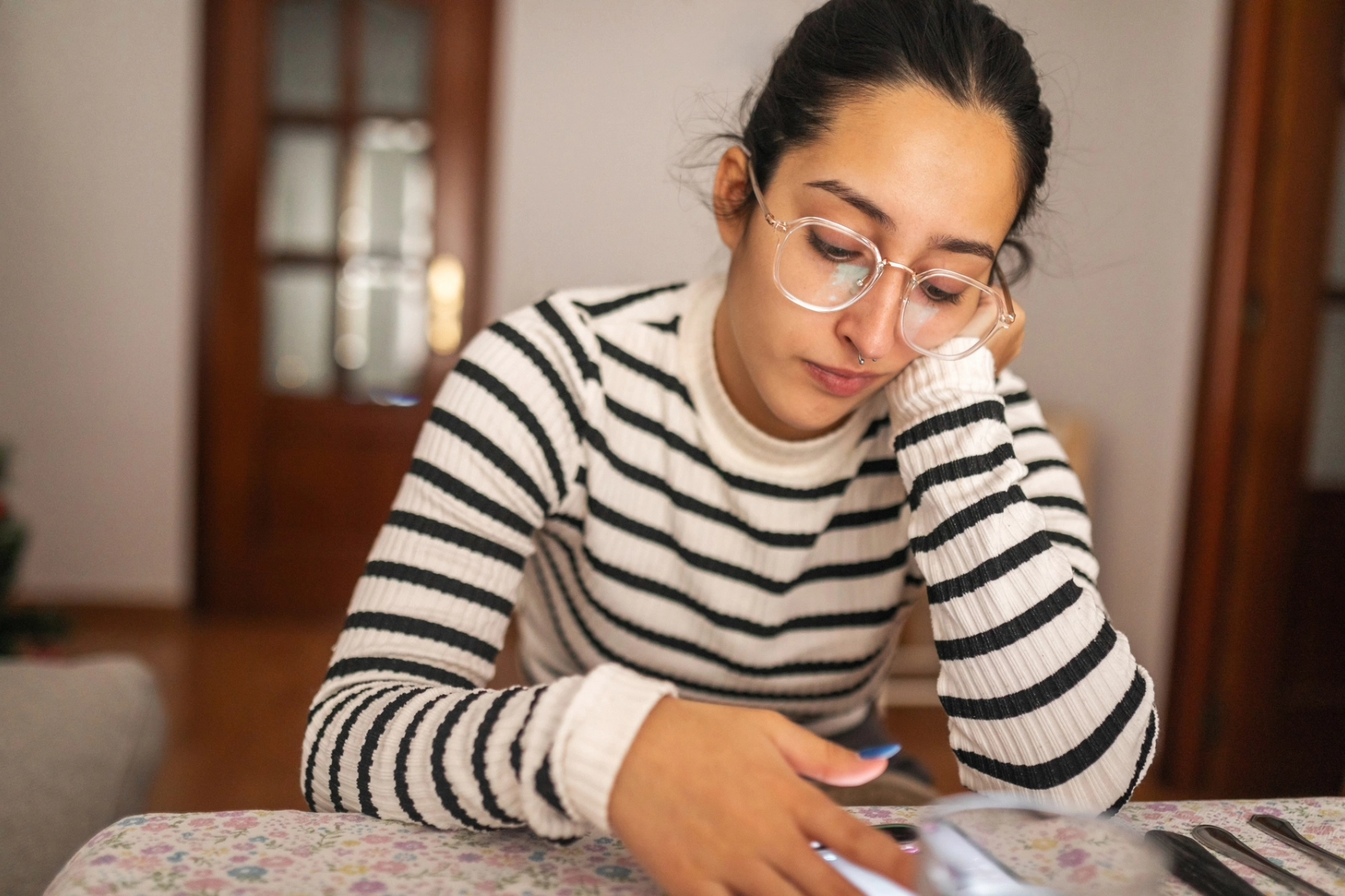 Woman sits at table as she posts a sadfishing comment on social media.