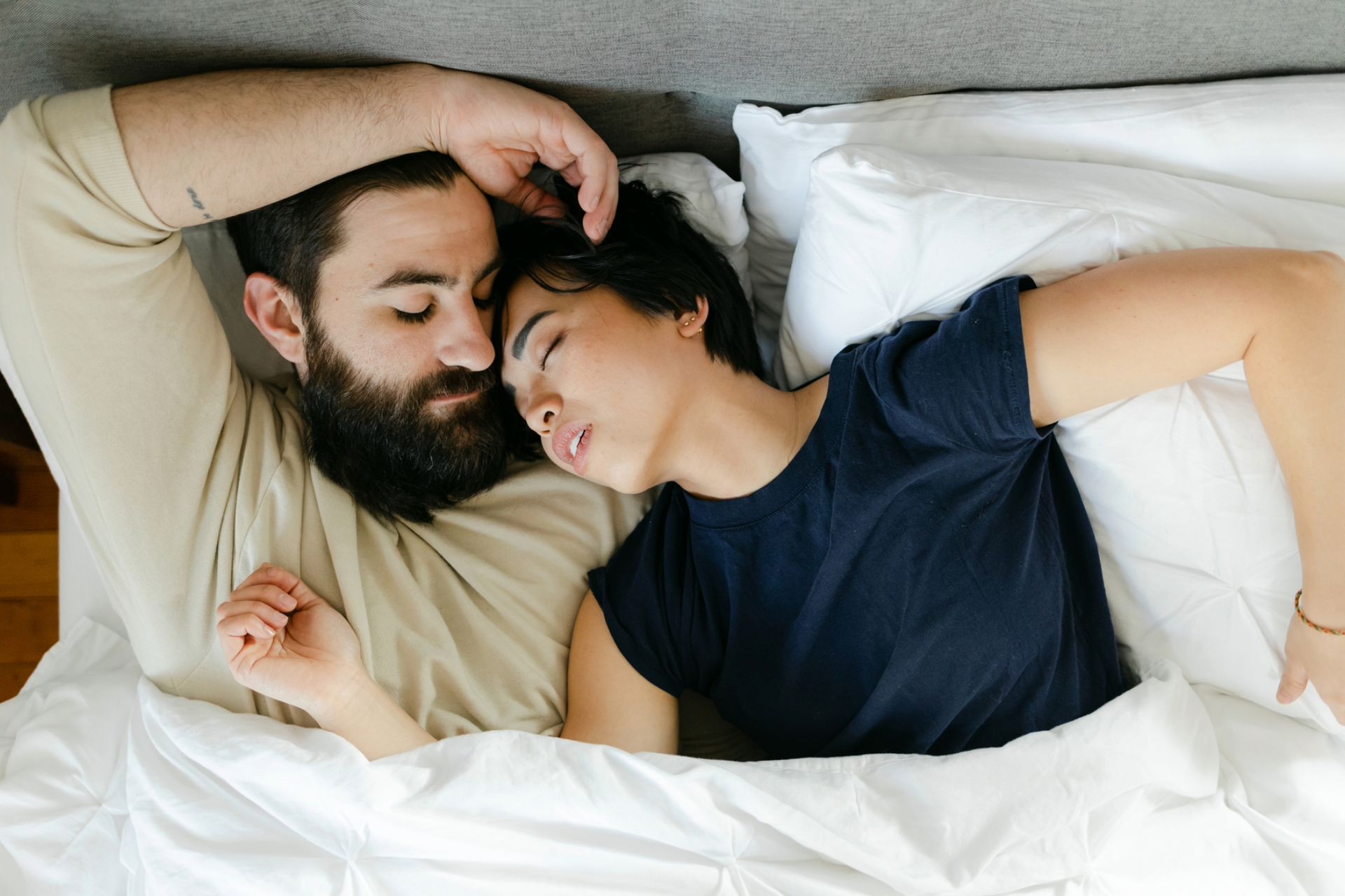 Couple fall asleep next to each other in bed, too tired to have sex after another long day.