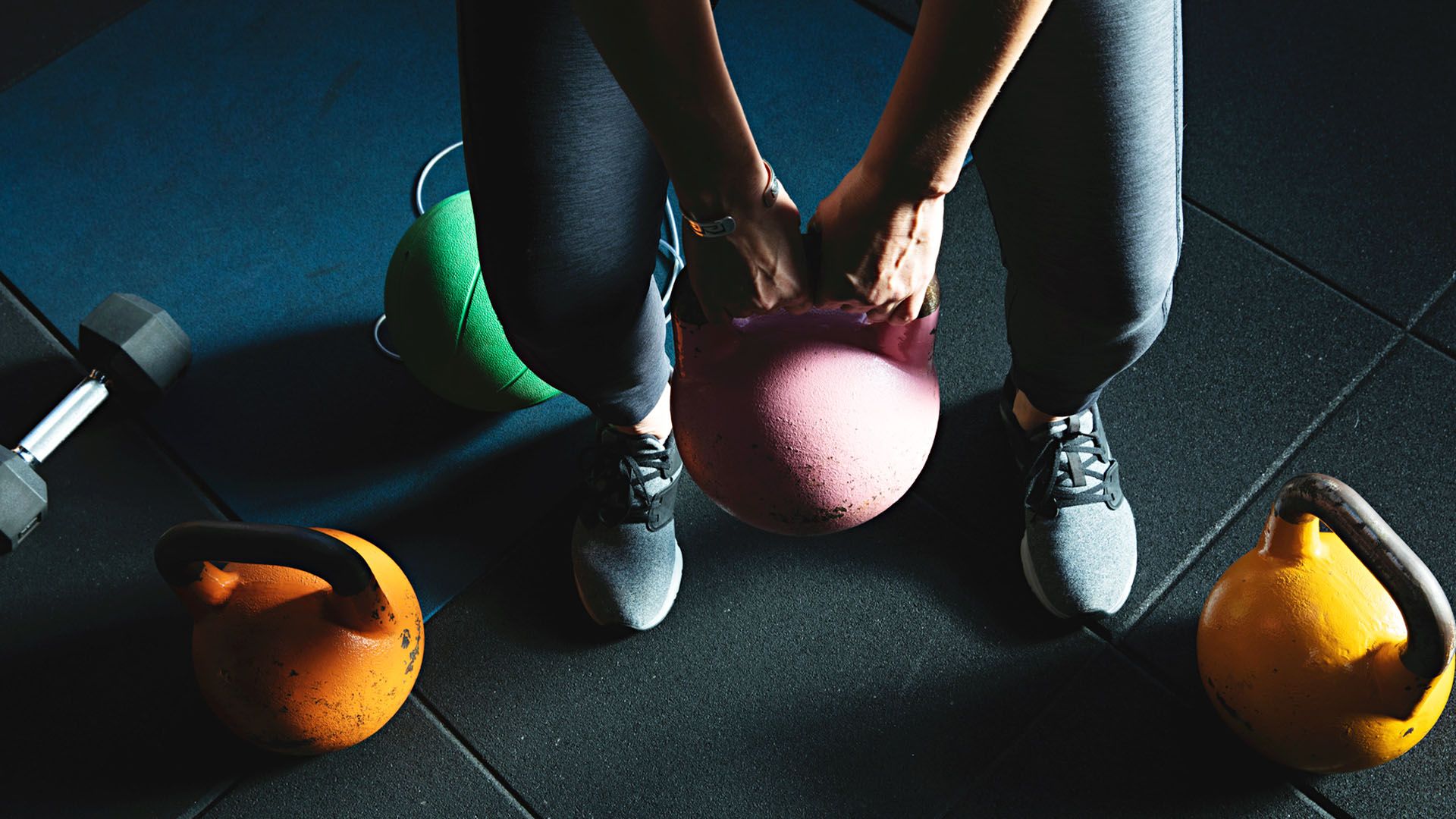 An array of colorful workout and weight training equipment on the floor of a gym 