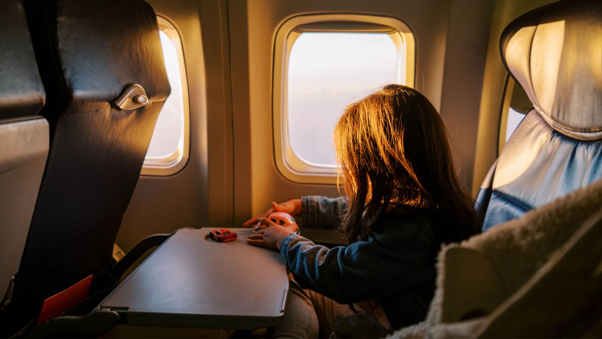 Child sitting by themself on the window seat on airplane