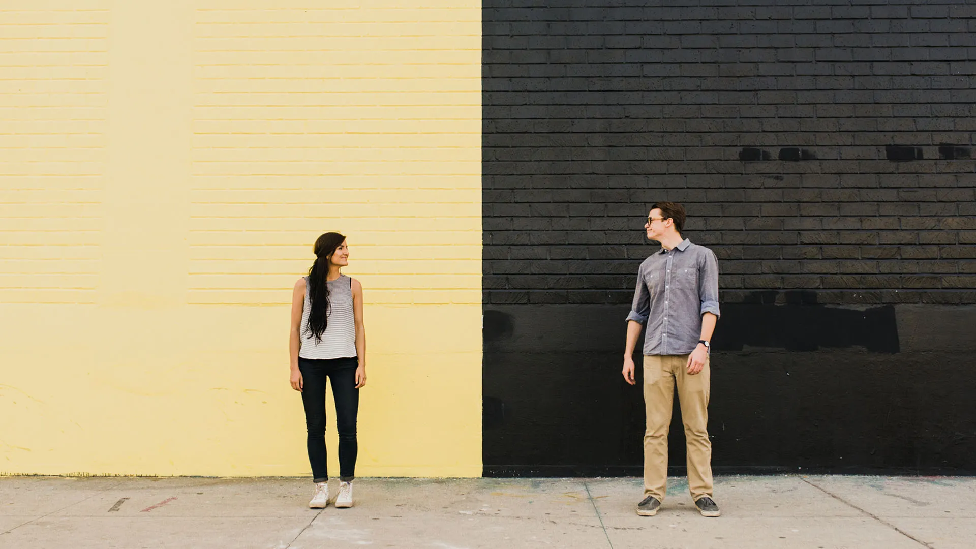 A man and a woman looking at each other from opposite colored backgrounds.