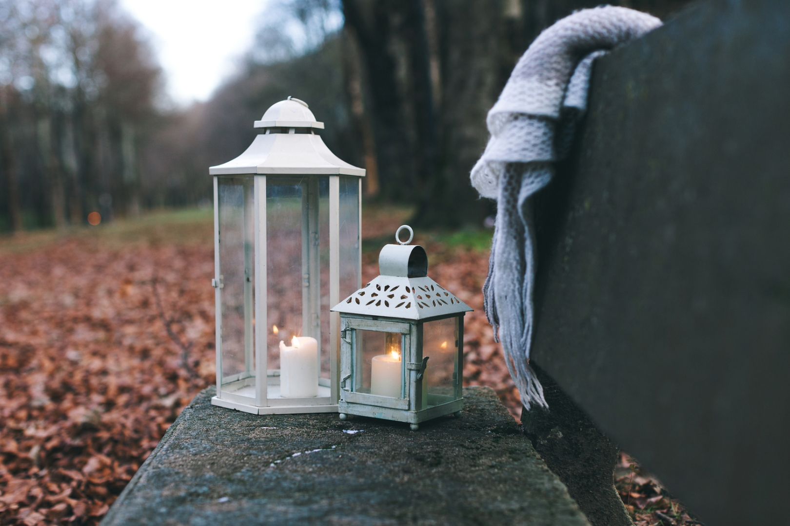 Lit white candles placed on a stone bench on a fall day represent some of the ways you can celebrate the autumn equinox.