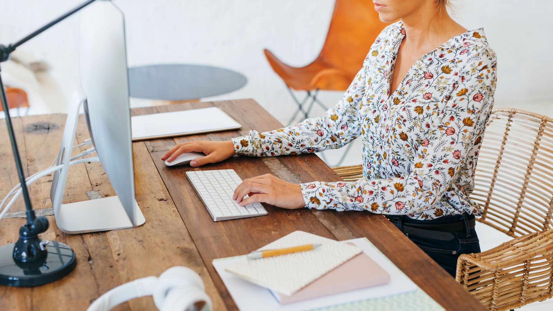 Woman working on a computer in a modern office with her desk set up at an appropriate eye level for good posture so she can avoid neck strain that might lead to a visible neck hump.