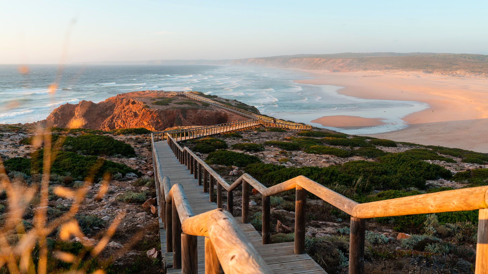 Sunset beach landscape with wooden path to the sea