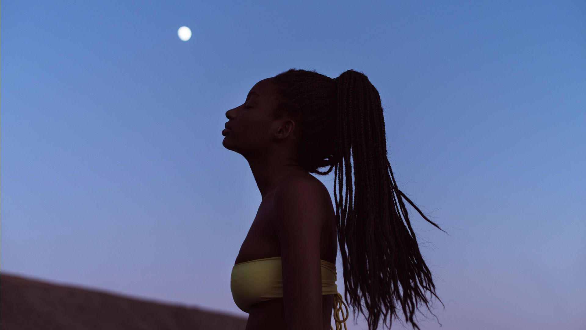 A young woman celebrates the summer solstice and looks up at at the moon on a beautiful evening