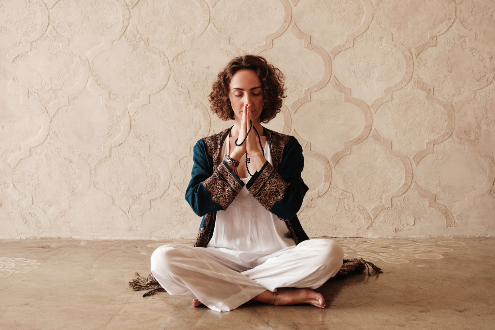 A woman sits with eyes closed and hands clasped, using meditation to stimulate the vagus nerve.