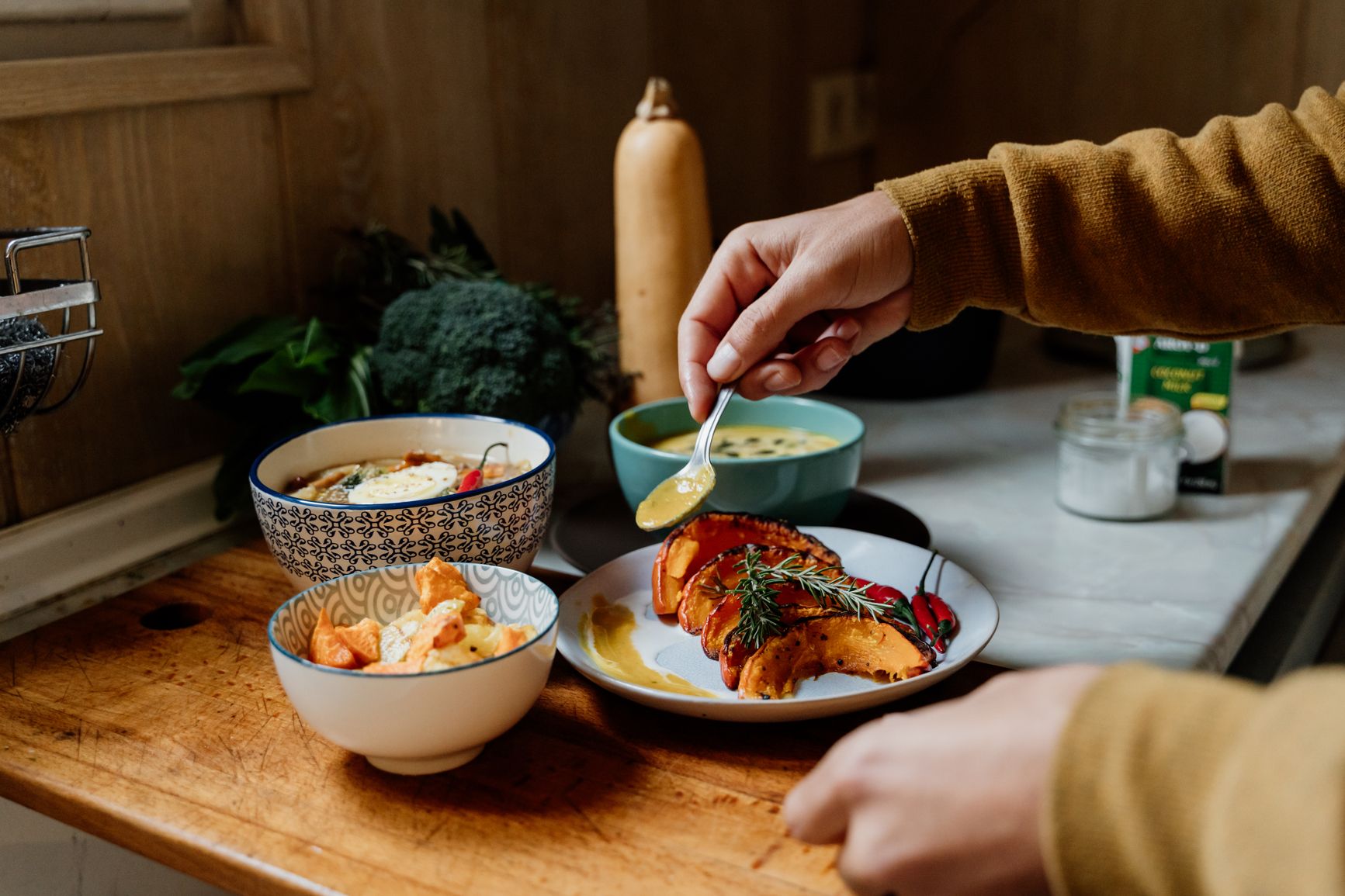 Photo of a person's hands as they prepare a colorful array of healthy-looking foods at a home countertop 