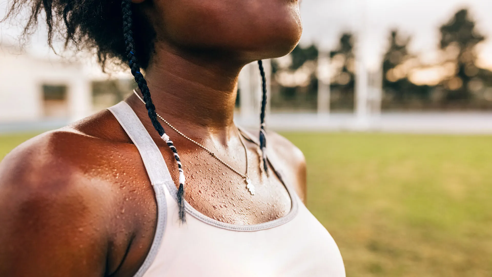 Athletic Black woman, shown from the chin down, stands sweating post workout.