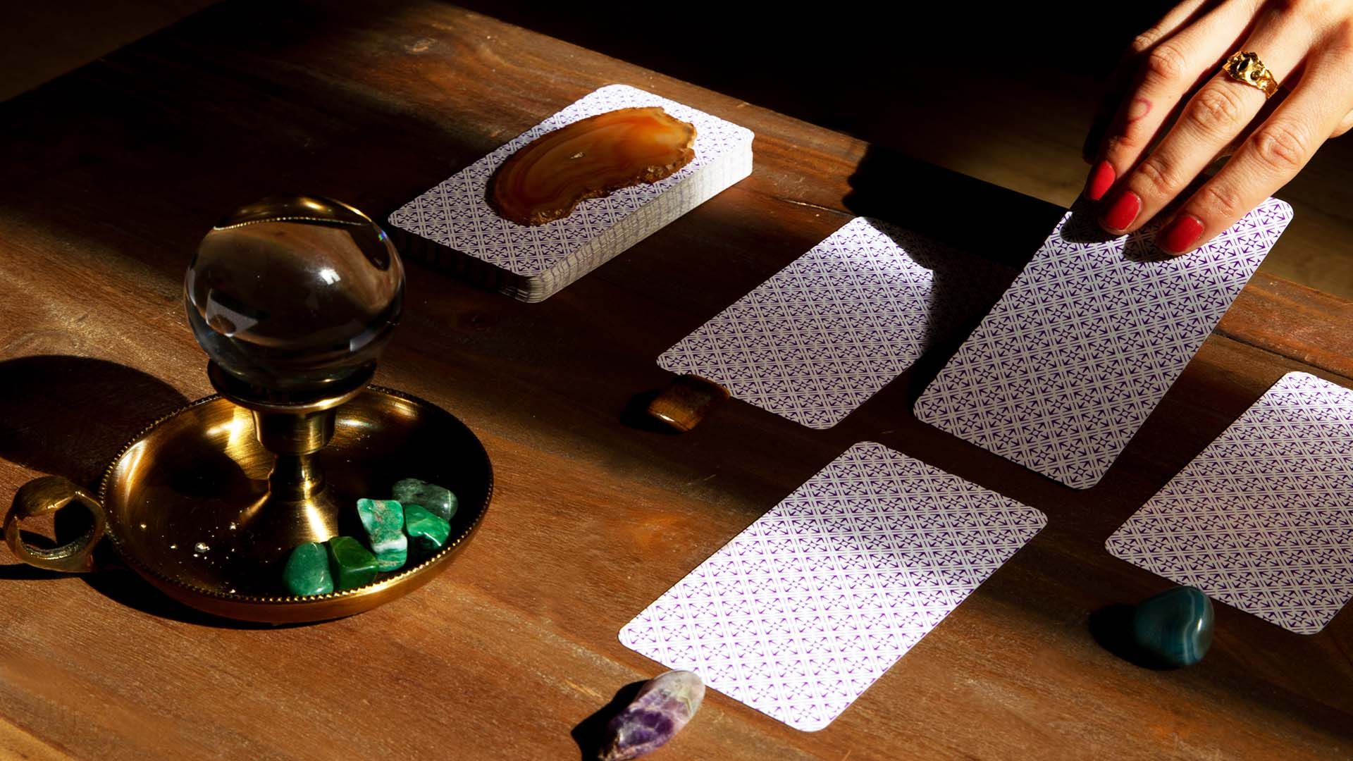 Woman's hand wearing red nail polish pulling tarot cards.