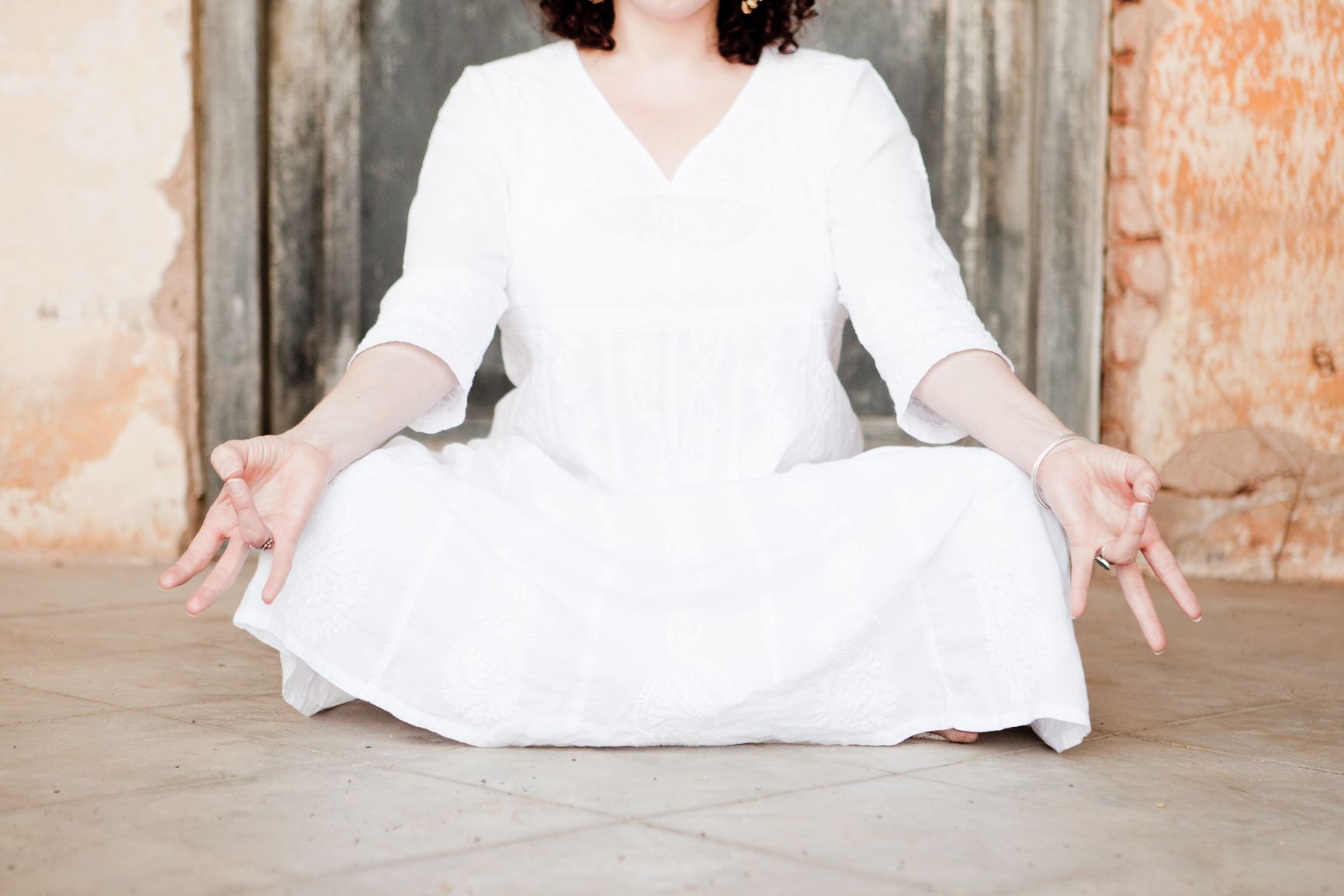 A kundalini yoga practitioner sits meditating in cross-legged pose while wearing white.