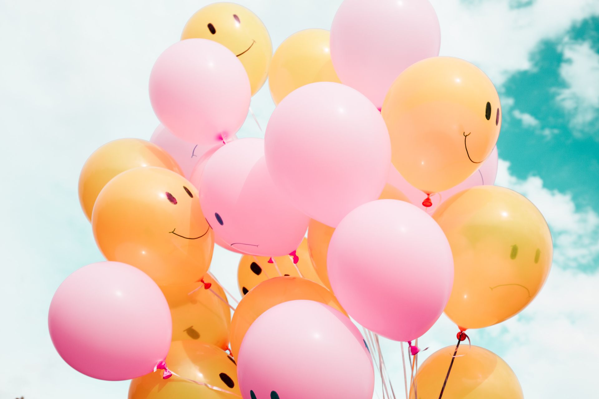 Pink and orange balloons against a blue sky